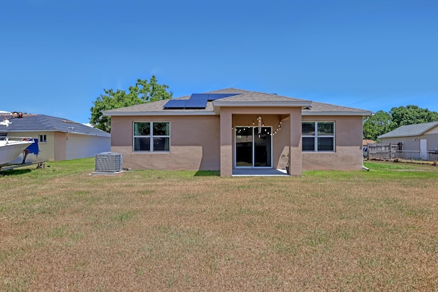 rear view of house featuring a lawn, solar panels, and central AC