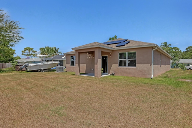 rear view of house with a lawn, solar panels, and central air condition unit