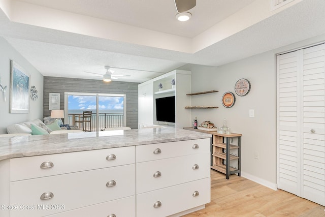 kitchen featuring white cabinetry, ceiling fan, light stone counters, and light hardwood / wood-style floors