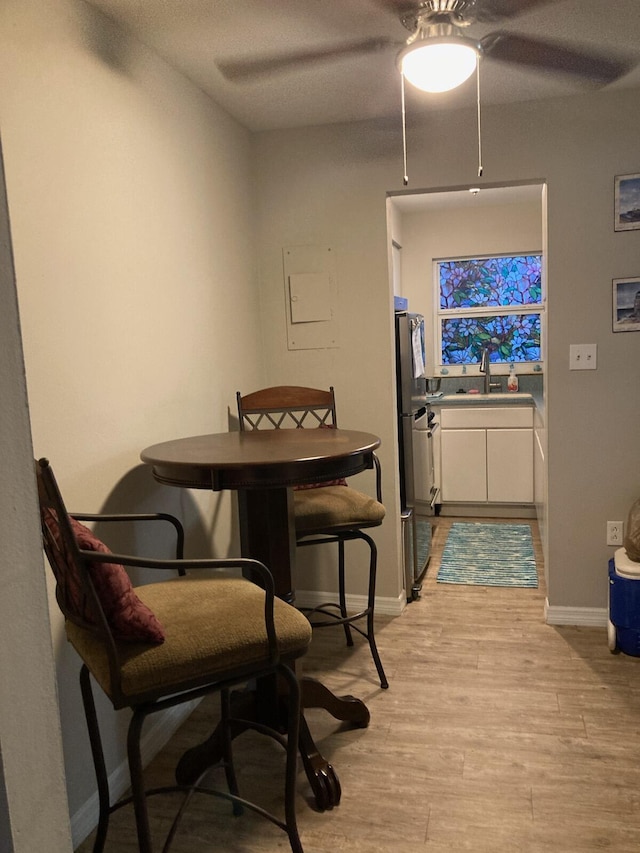 dining room featuring light hardwood / wood-style floors, ceiling fan, and sink