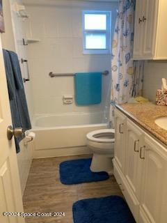 full bathroom with hardwood / wood-style flooring, shower / bath combo with shower curtain, vanity, and toilet