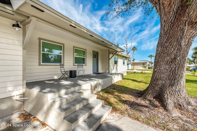 view of exterior entry with covered porch and a yard