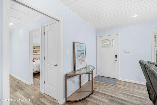 foyer entrance featuring wooden ceiling, ornamental molding, and light wood-type flooring