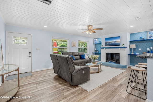 living room with light wood-type flooring, a brick fireplace, ceiling fan, and wooden ceiling