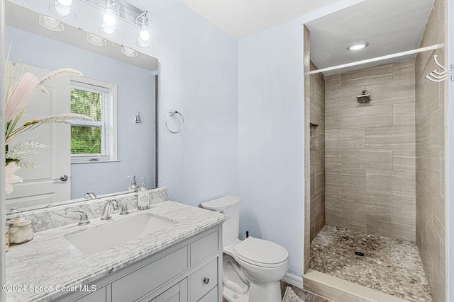 bathroom with tiled shower, vanity, and toilet