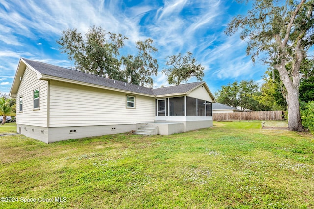 rear view of property with a yard and a sunroom