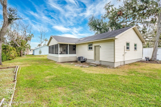 rear view of house with a yard, central AC, and a sunroom