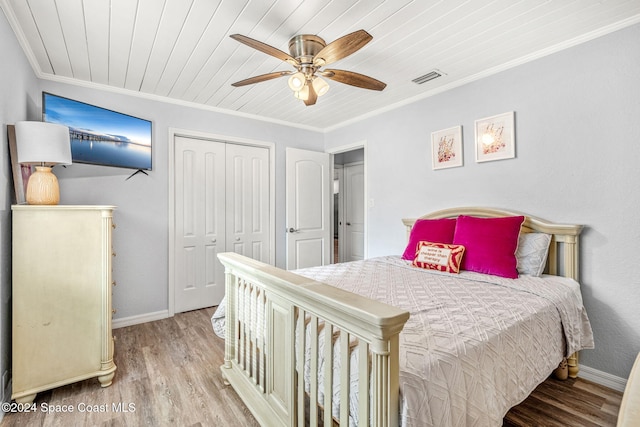 bedroom featuring ceiling fan, crown molding, a closet, wood ceiling, and light wood-type flooring