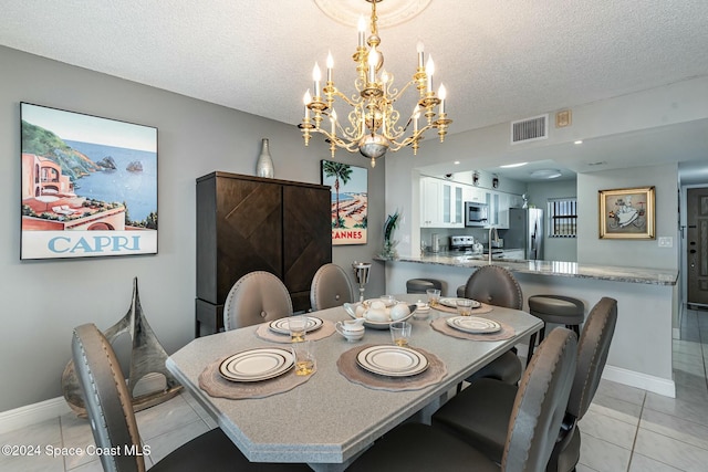 tiled dining area with sink, a textured ceiling, and a chandelier