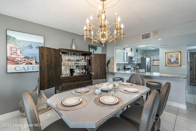 dining space with sink, light tile patterned flooring, a textured ceiling, and a notable chandelier