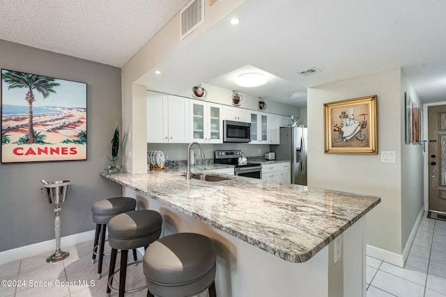 kitchen featuring kitchen peninsula, appliances with stainless steel finishes, a breakfast bar, sink, and white cabinets