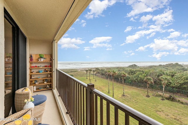 balcony with a water view and a view of the beach