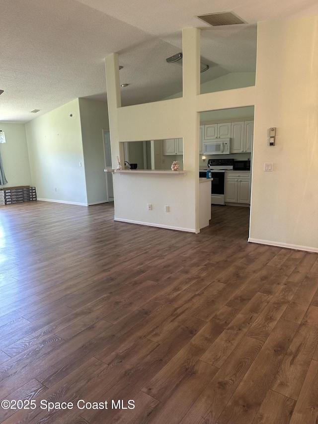 unfurnished living room with baseboards, visible vents, vaulted ceiling, and dark wood-type flooring