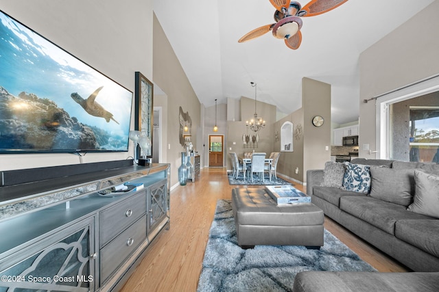 living room with ceiling fan with notable chandelier, light wood-type flooring, and high vaulted ceiling