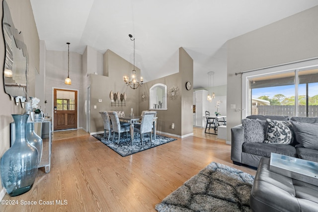 living room with hardwood / wood-style floors, high vaulted ceiling, and an inviting chandelier