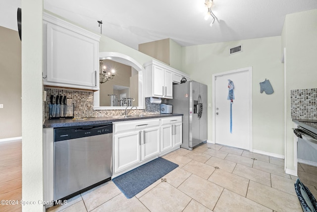 kitchen with white cabinets, decorative backsplash, appliances with stainless steel finishes, and an inviting chandelier