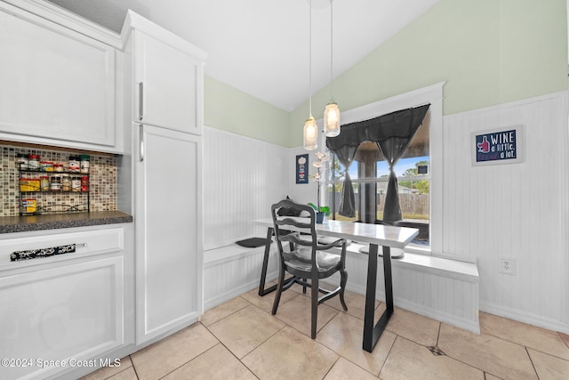 tiled dining area featuring vaulted ceiling