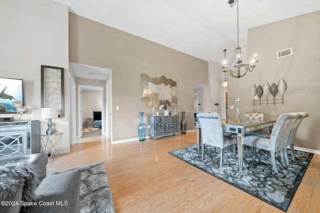 dining room with a chandelier, a towering ceiling, and wood-type flooring