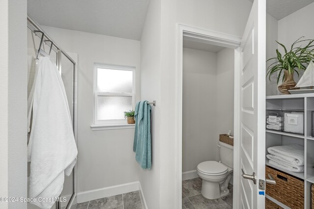 bathroom with tile patterned floors, toilet, and walk in shower