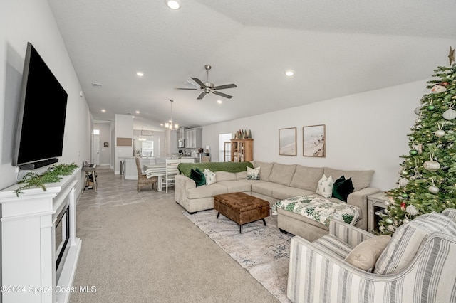 carpeted living room with ceiling fan with notable chandelier, a textured ceiling, and vaulted ceiling