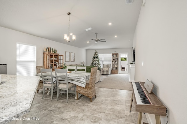 dining area featuring ceiling fan with notable chandelier, light colored carpet, and vaulted ceiling