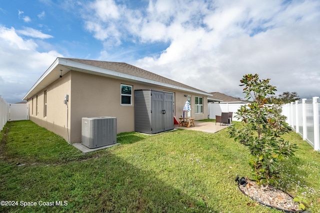 rear view of property with a lawn, central AC, and a patio area