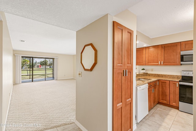 kitchen with sink, light tile patterned floors, a textured ceiling, and appliances with stainless steel finishes