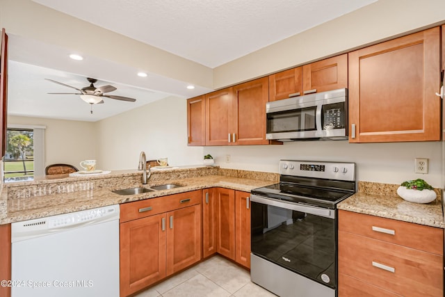 kitchen with light stone countertops, sink, stainless steel appliances, kitchen peninsula, and light tile patterned floors