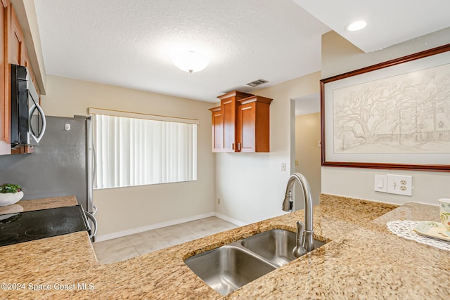 kitchen featuring kitchen peninsula, sink, light tile patterned flooring, and a textured ceiling