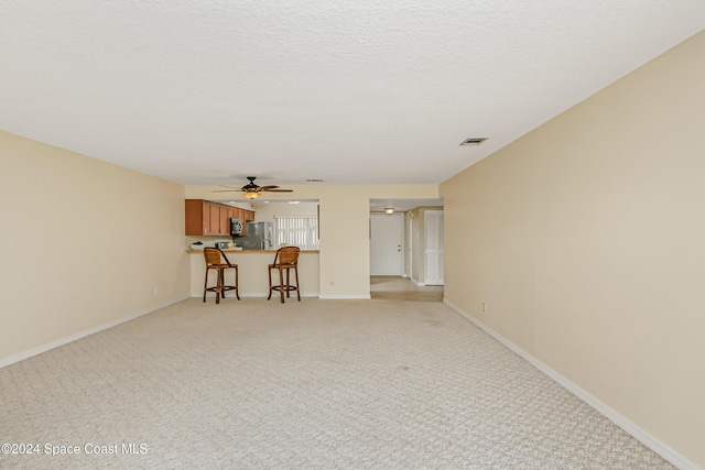 unfurnished living room with ceiling fan and light colored carpet