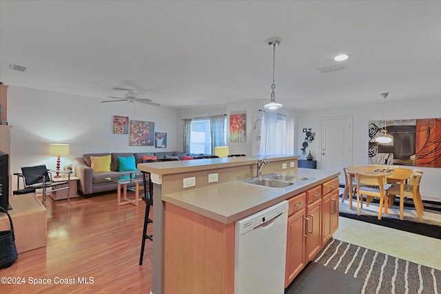 kitchen with white dishwasher, decorative light fixtures, sink, and a kitchen island with sink