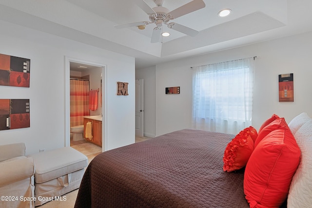 bedroom featuring ceiling fan, a raised ceiling, and ensuite bathroom