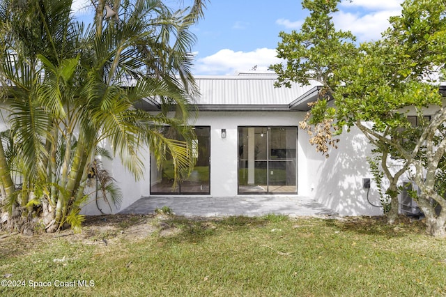 rear view of property featuring a patio area and a lawn