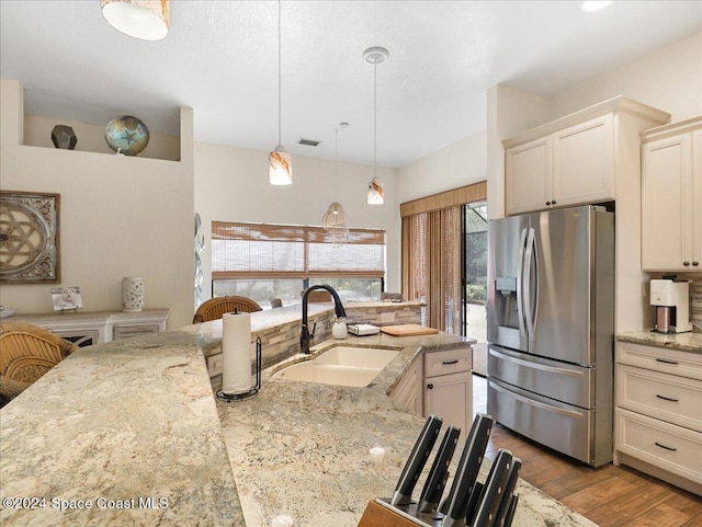 kitchen featuring light stone countertops, stainless steel refrigerator with ice dispenser, light wood-type flooring, and sink