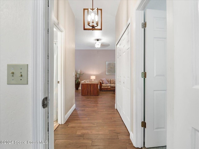 hallway with dark hardwood / wood-style floors and an inviting chandelier