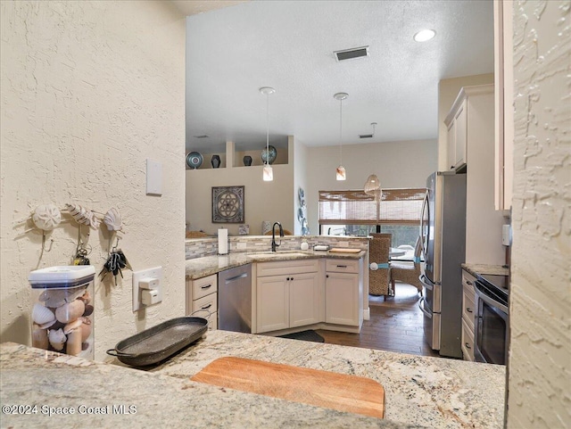 kitchen featuring hanging light fixtures, sink, light stone counters, appliances with stainless steel finishes, and dark hardwood / wood-style flooring