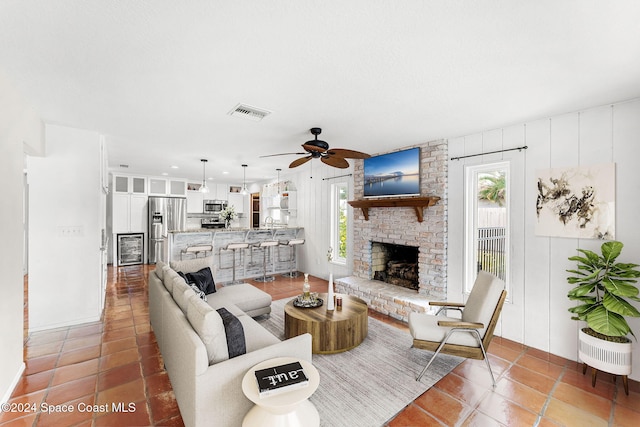 tiled living room featuring ceiling fan and a brick fireplace