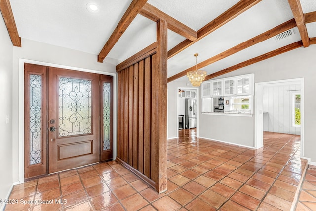 foyer entrance with lofted ceiling with beams, a textured ceiling, and a notable chandelier