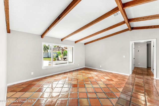 spare room featuring a textured ceiling, vaulted ceiling with beams, and tile patterned floors