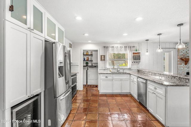 kitchen featuring white cabinets, hanging light fixtures, sink, light stone countertops, and appliances with stainless steel finishes