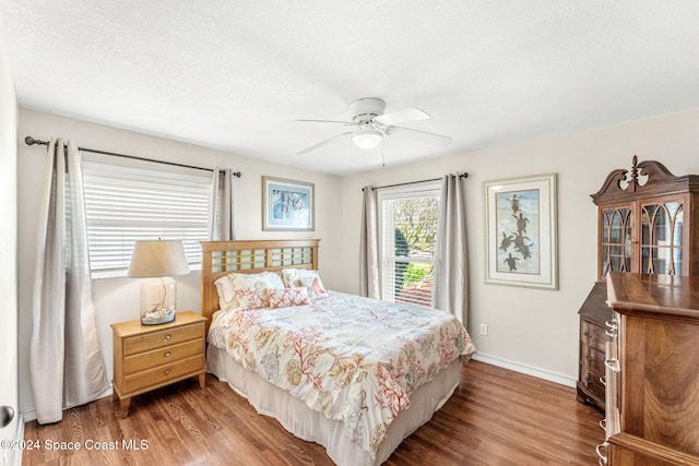 bedroom with a textured ceiling, ceiling fan, and dark hardwood / wood-style floors