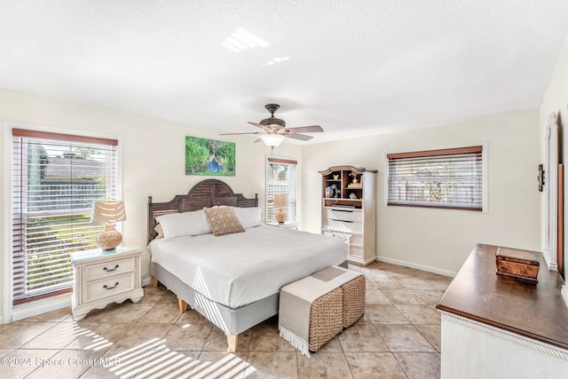 bedroom featuring ceiling fan, light tile patterned flooring, and a textured ceiling