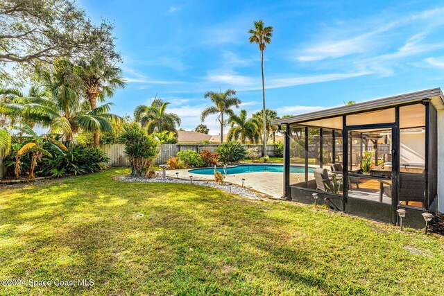 view of yard featuring a fenced in pool, a sunroom, and a patio