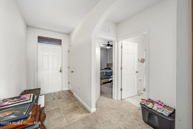 entrance foyer featuring light carpet, ceiling fan, and a textured ceiling