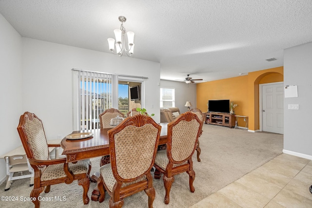 dining area with ceiling fan with notable chandelier, light colored carpet, and a textured ceiling