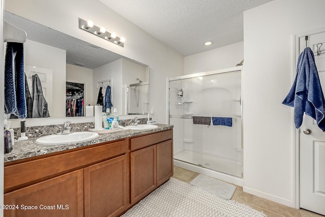 bathroom featuring tile patterned flooring, vanity, a shower with shower door, and a textured ceiling