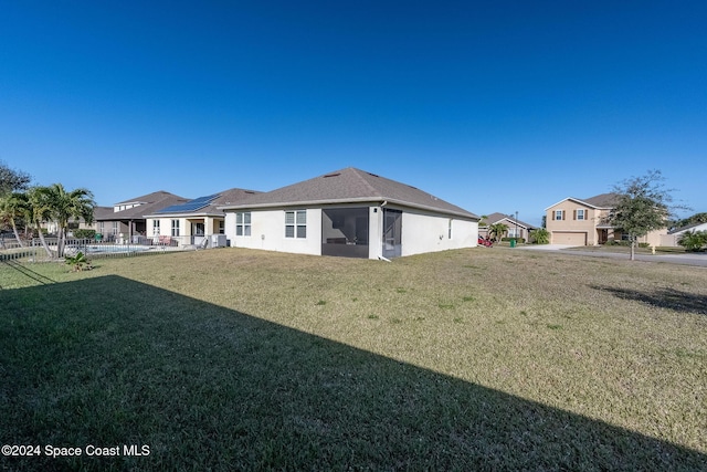 rear view of property with a lawn, a sunroom, and a garage