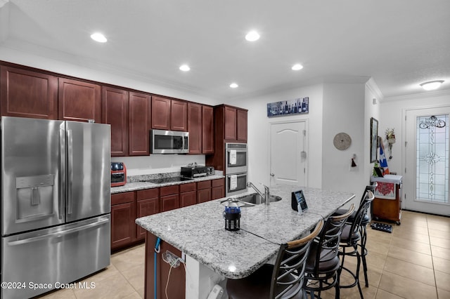 kitchen featuring sink, a breakfast bar area, ornamental molding, an island with sink, and stainless steel appliances