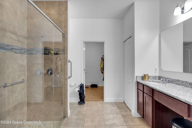 bathroom with tile patterned flooring, vanity, and walk in shower