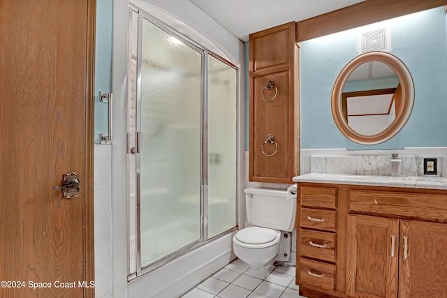 bathroom featuring tile patterned floors, vanity, a shower with shower door, and toilet